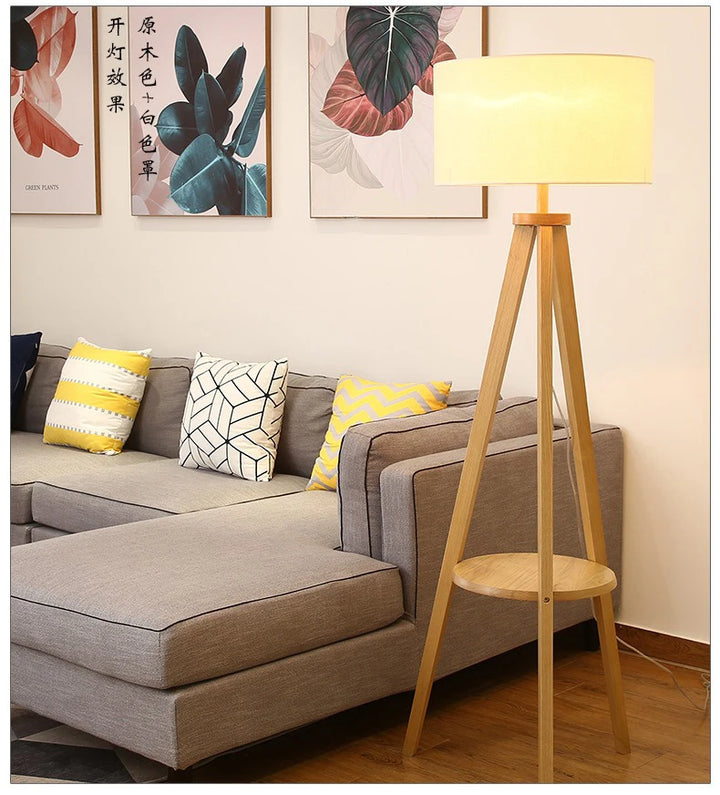 Wooden floor lamp next to a gray sofa with decorative pillows in a living room setting.