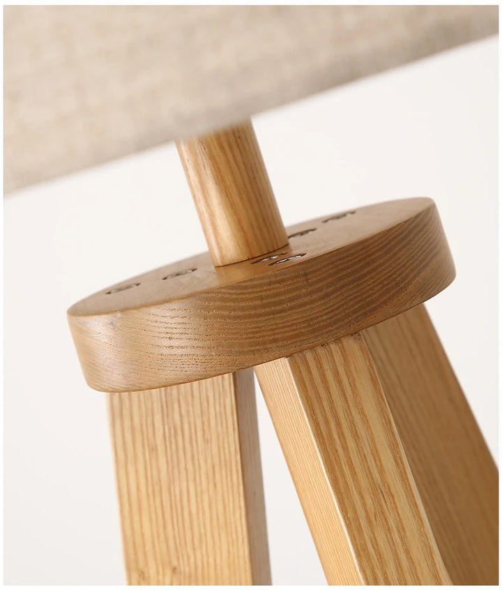Close-up of a wooden stool with a beige cushioned seat on a light background
