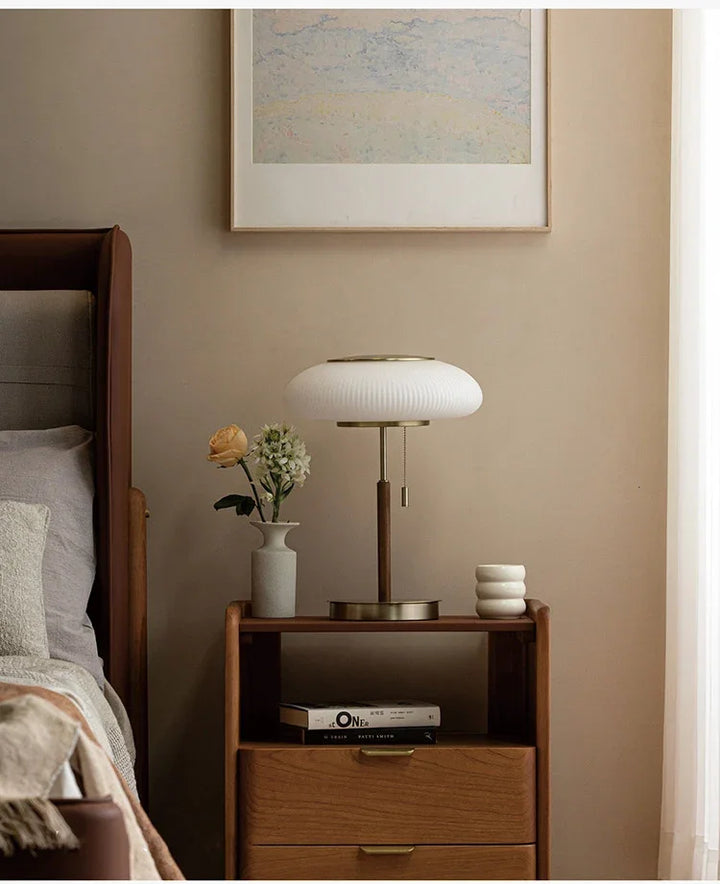 Wooden nightstand with lamp and decorative items against a beige wall