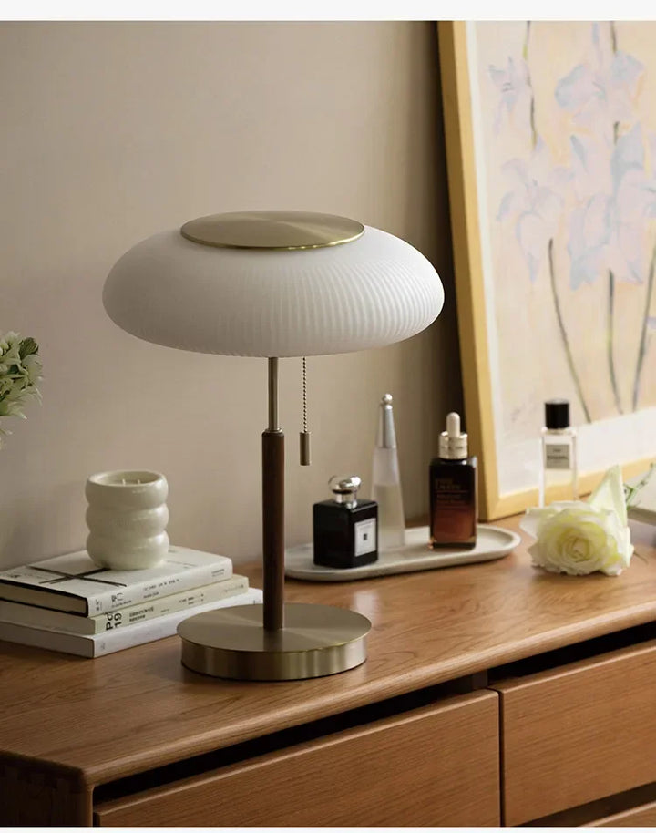 Table lamp on a wooden surface with decorative items in a room setting