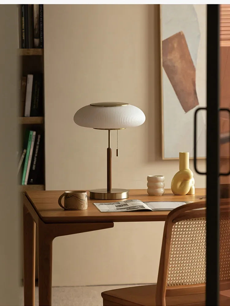 Modern desk setup with a lamp, books, and a chair in a room.