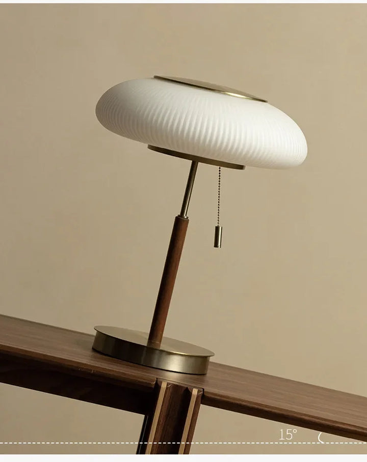 Modern table lamp with white shade and wooden base on a wooden surface.