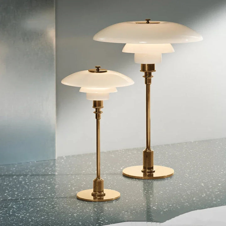 Two brass table lamps with white glass shades on a reflective surface.