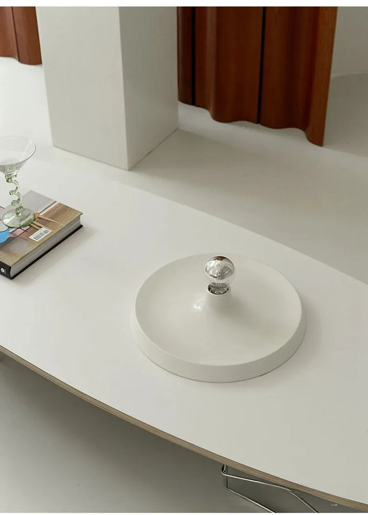 White ceiling lamp with a transparent bulb on a white surface