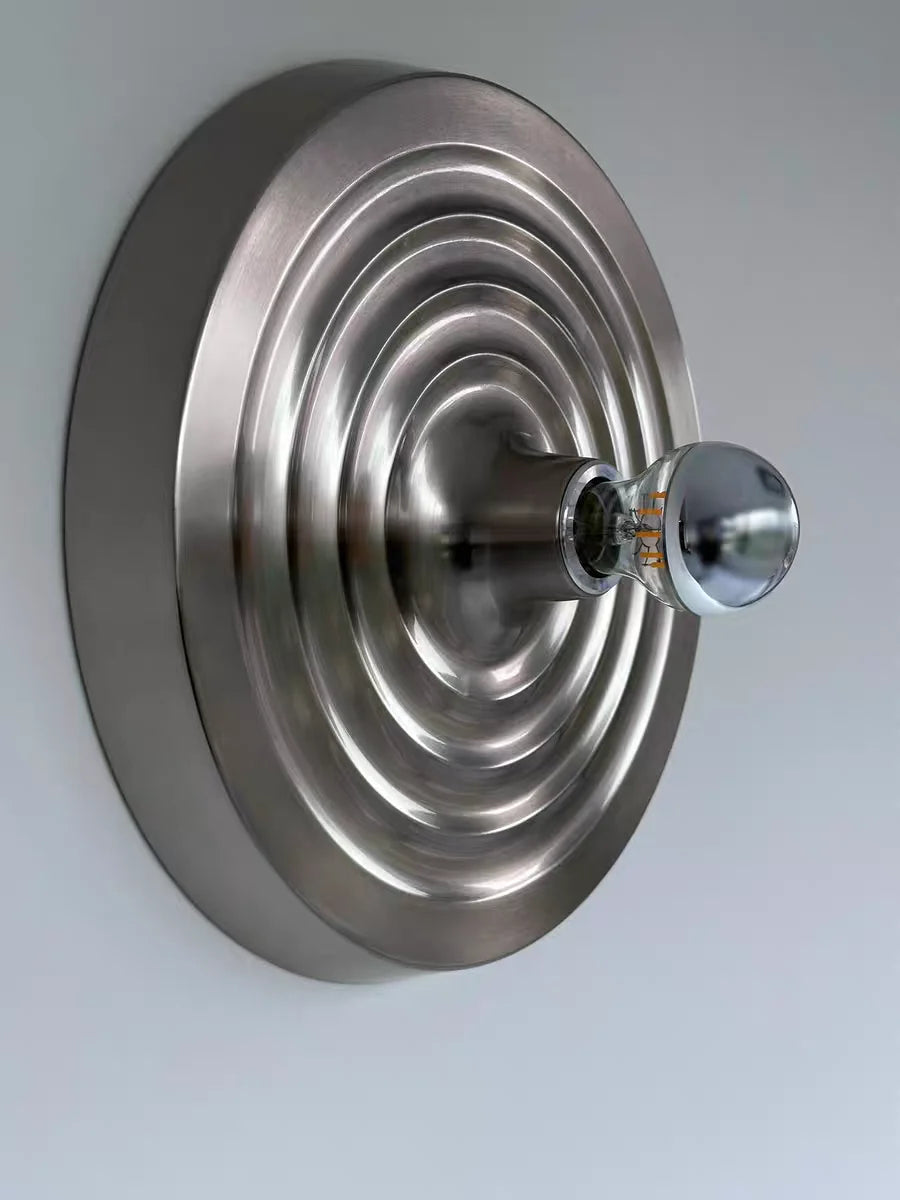 Metallic wall-mounted fixture with a round design on a light gray background