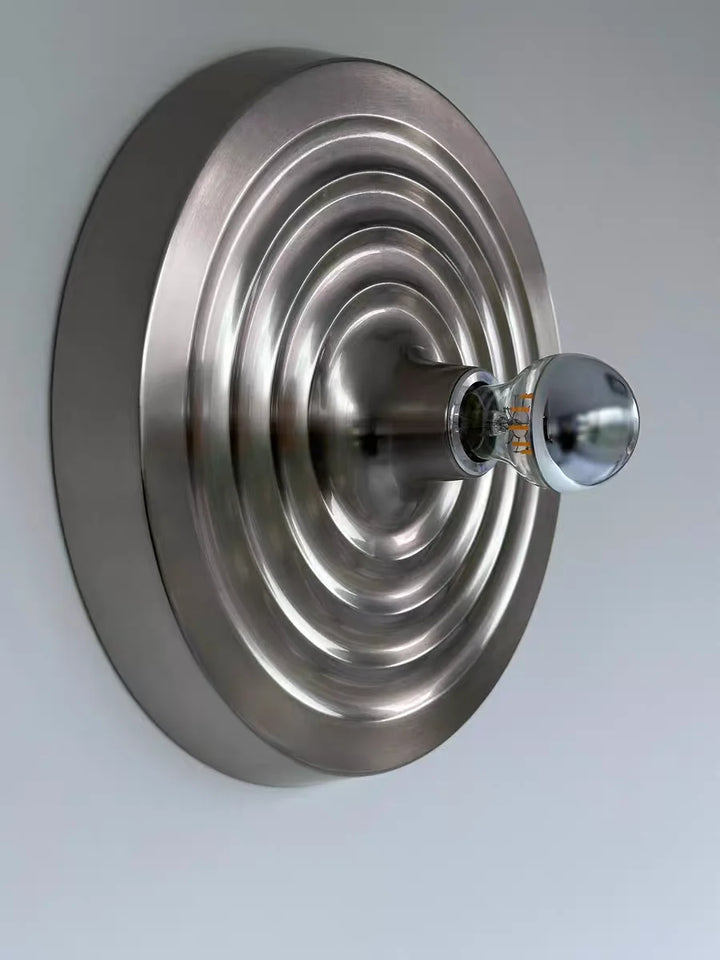Metallic wall-mounted fixture with a round design on a light gray background