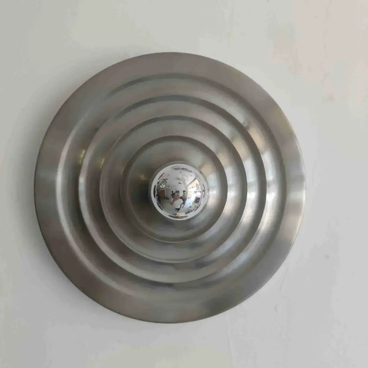 Metallic circular object with concentric rings on a white background