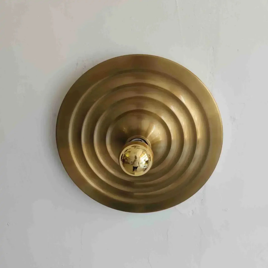 Brass circular object with concentric rings on a light gray background