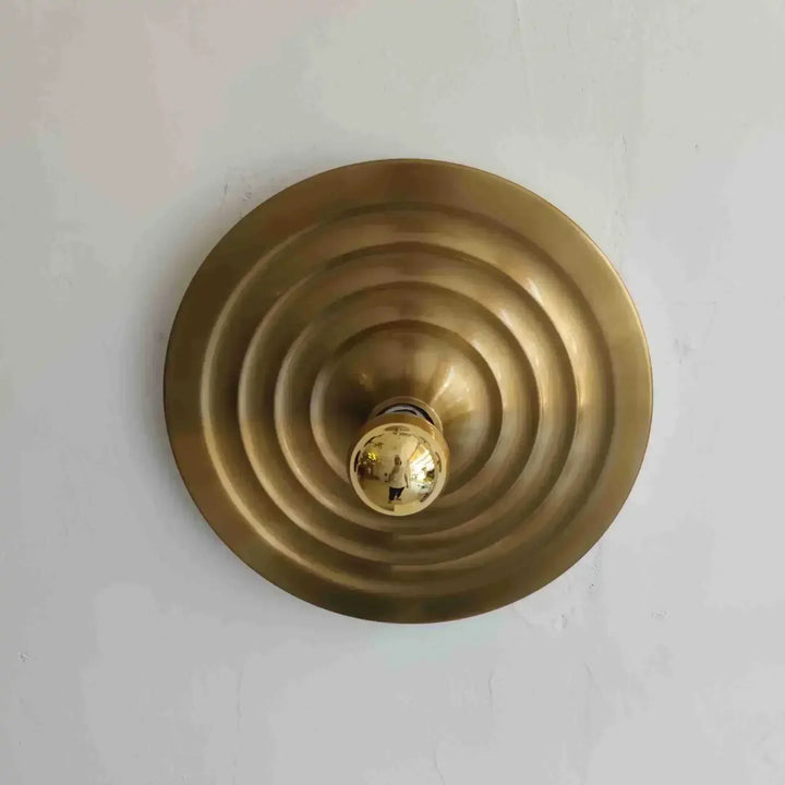 Brass circular object with concentric rings on a light gray background