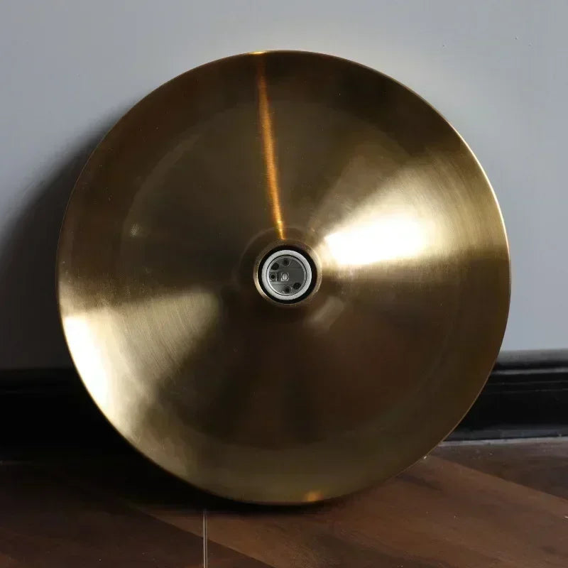 Gold-colored metal object with a central circular component on a wooden surface.