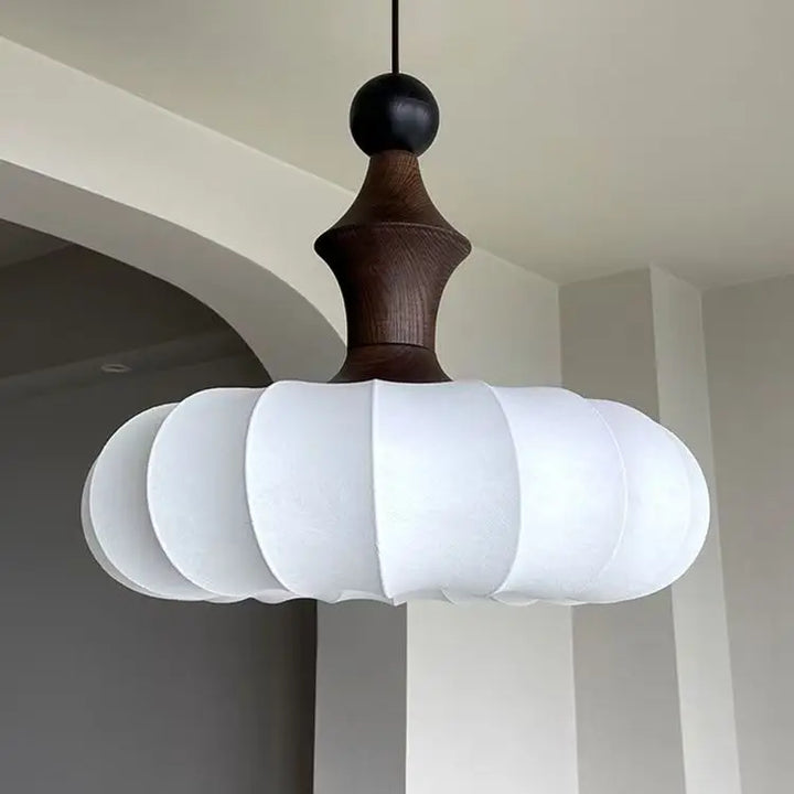 Modern pendant light with white lampshade and wooden fixture hanging in a room.