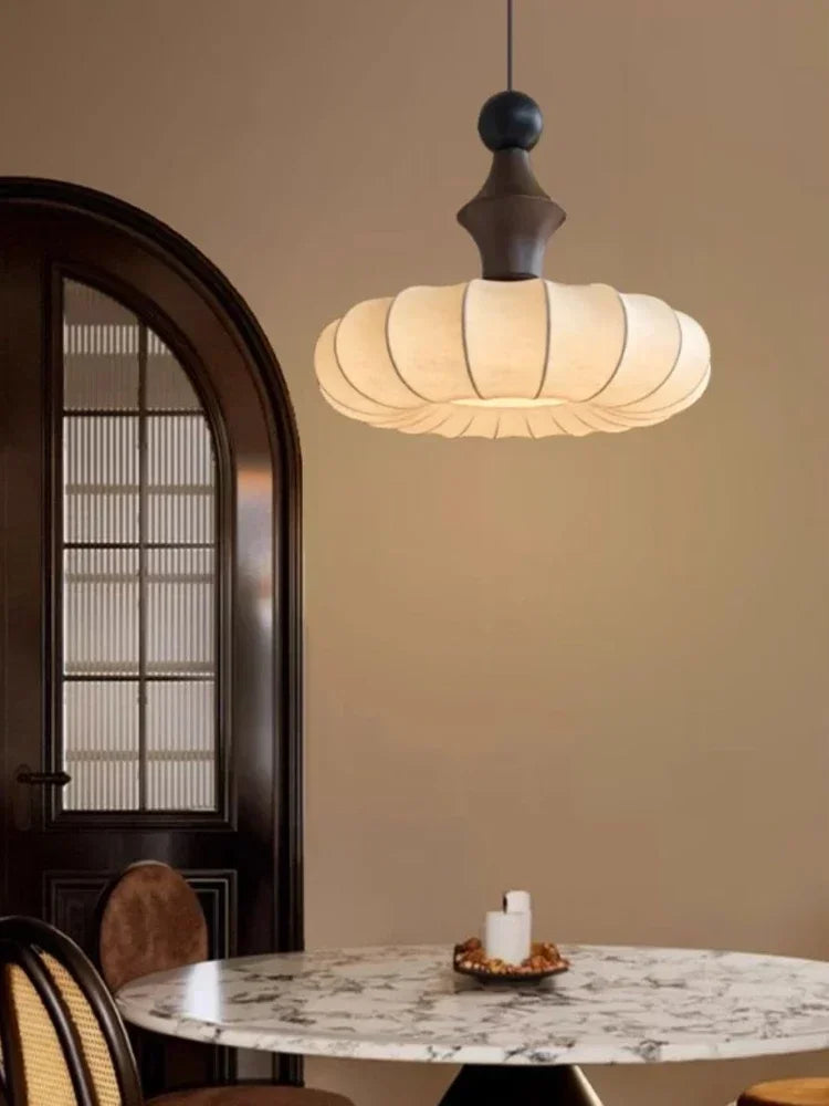 Modern pendant light hanging above a marble table in a room with a door and candle.