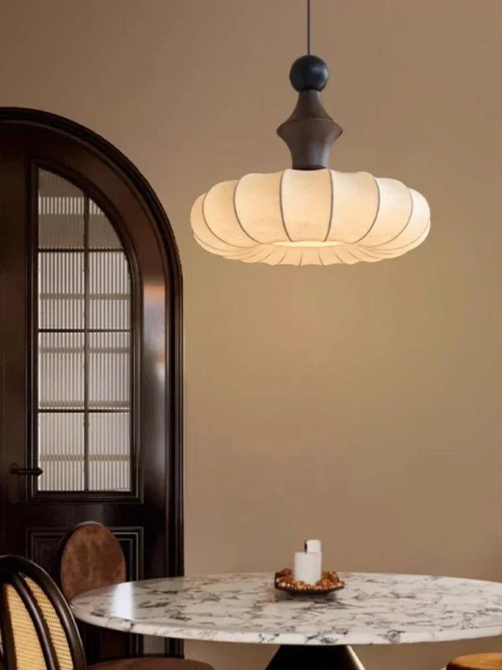 Modern pendant light hanging above a marble table in a room with a door and candle.