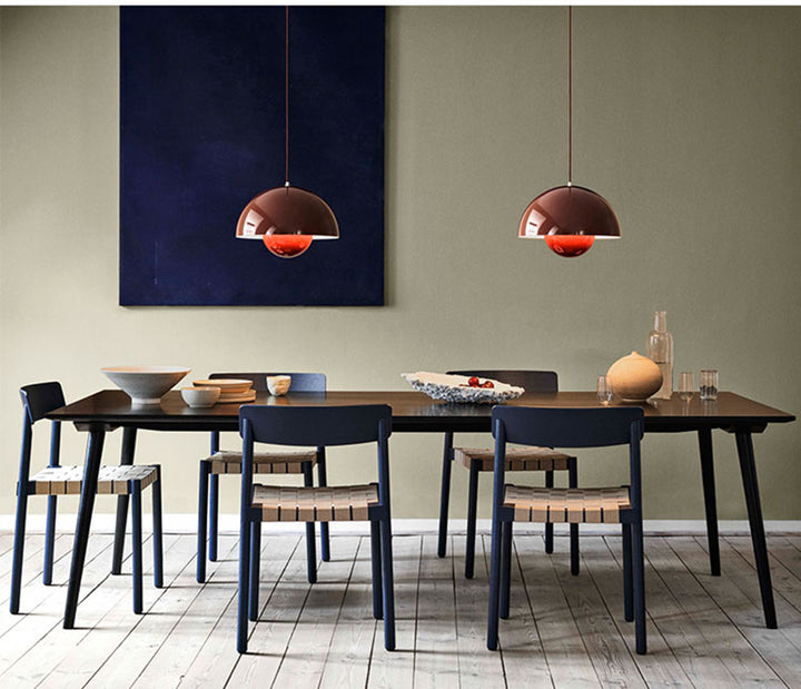 Dining room with a long wooden table and chairs, featuring two pendant lights and a painting on the wall.