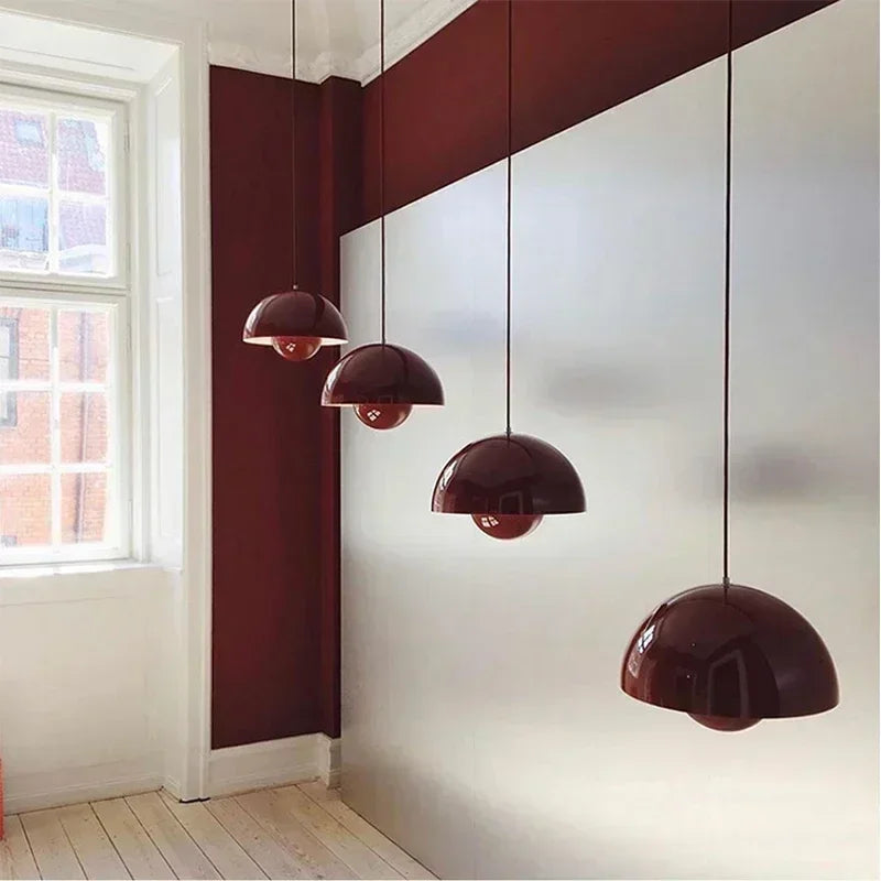 Modern pendant lights hanging in a room with a window and red wall.