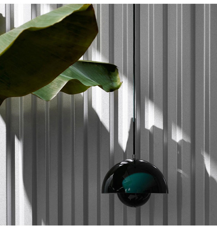 Modern green pendant light with a green glass shade against a striped wall.