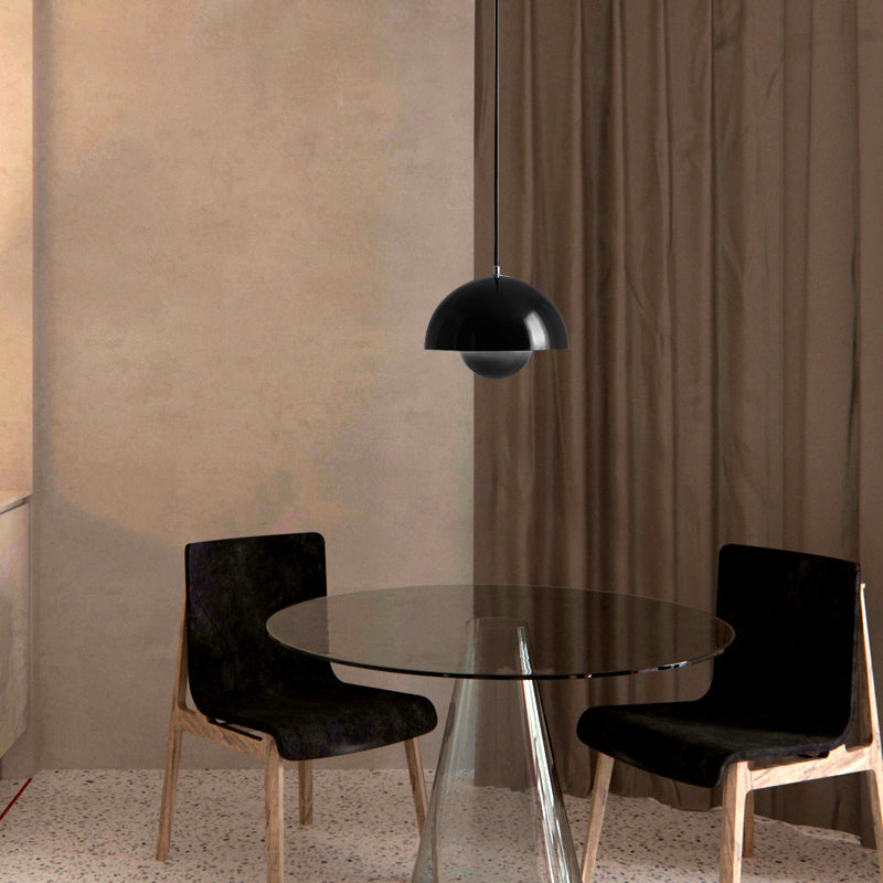 Modern dining area with a round glass table and black chairs in a room with beige walls and brown curtains.