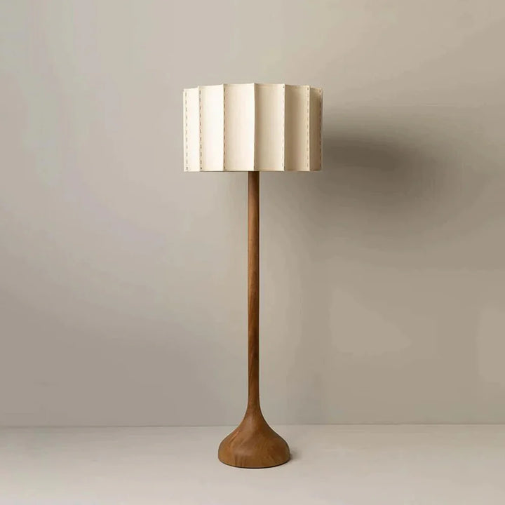 Tall floor lamp with a wooden base and gold lampshade on a plain background
