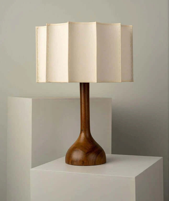 Table lamp with wooden base and beige fabric shade on a neutral background