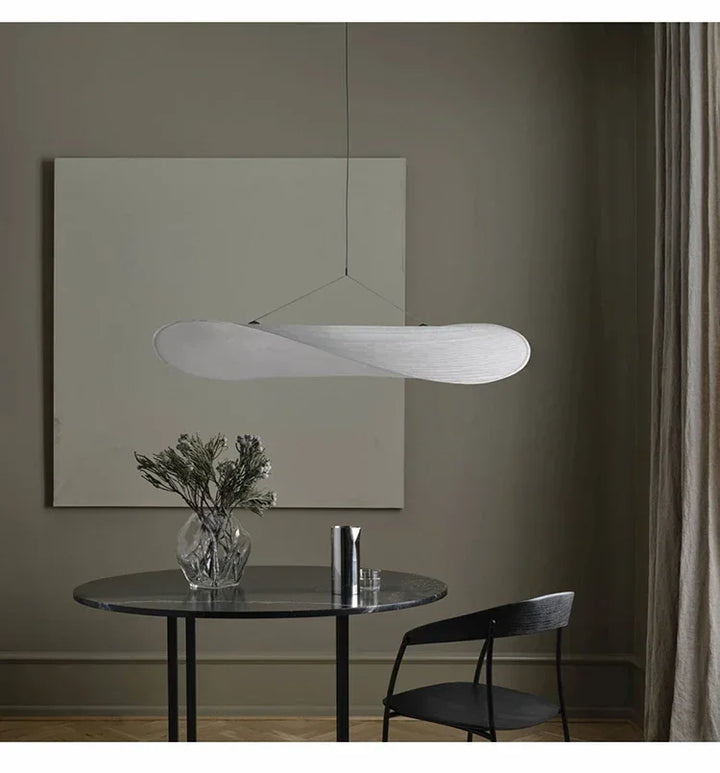 Modern pendant light hanging above a dining table with a minimalistic decor.