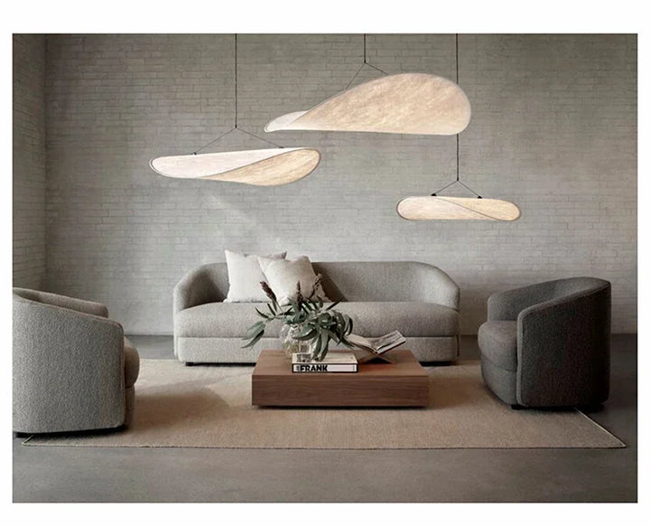 Modern living room with gray sofa, armchairs, and pendant lights.