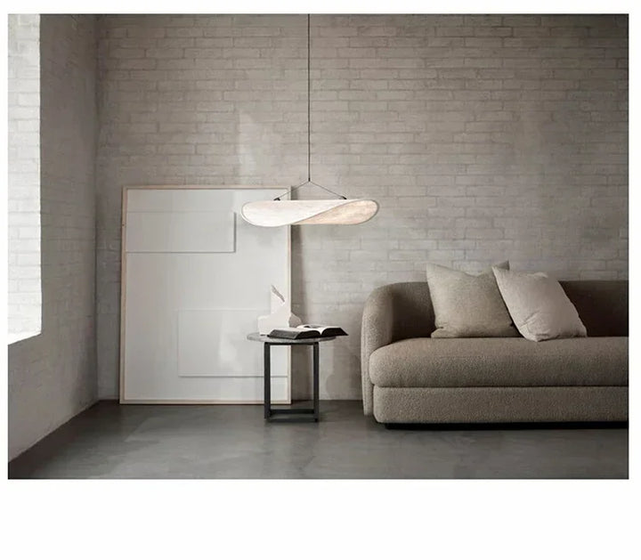 Modern living room with a gray sofa, side table, and pendant light.