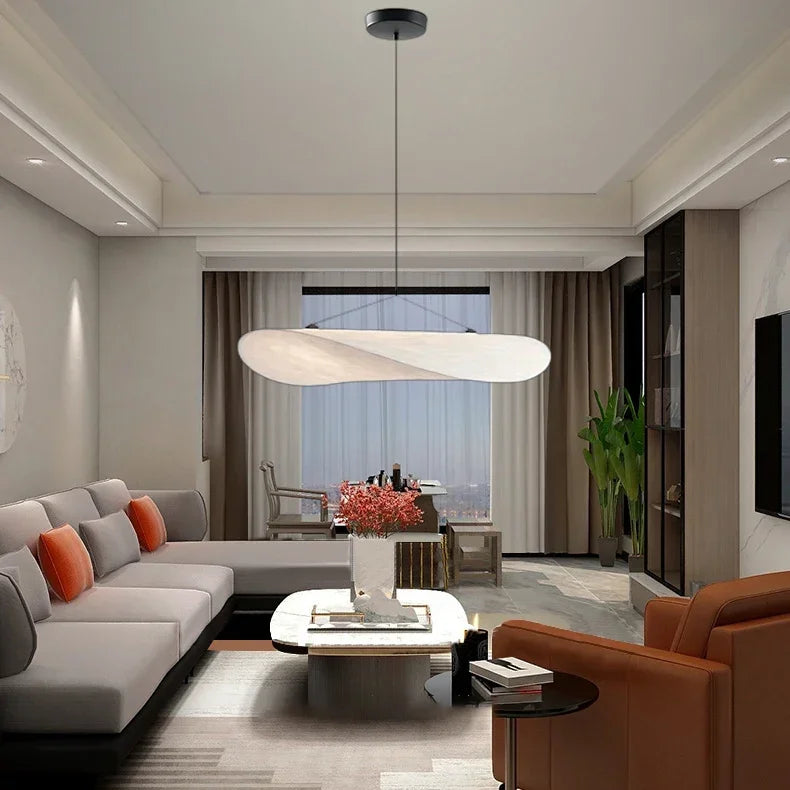 Modern living room with gray sectional sofa, brown armchair, and large pendant light.