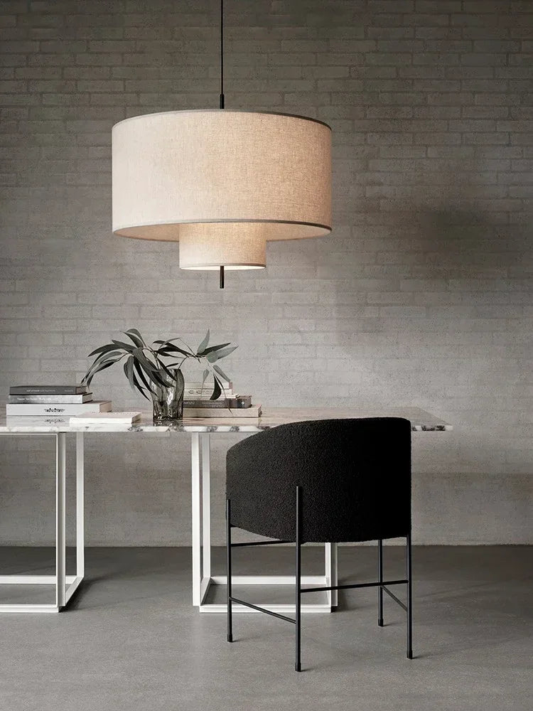 Modern dining area with a pendant lamp, table, and chair against a gray brick wall.