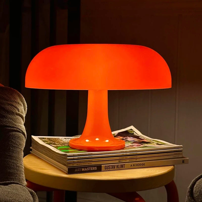 Orange table lamp on a stack of magazines with a warm glow