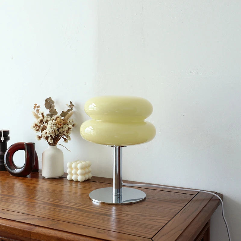 Yellow table lamp on a wooden surface with decorative items against a white wall
