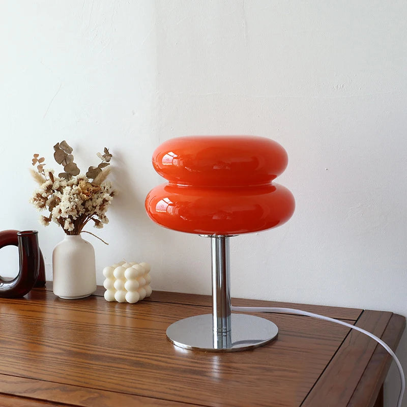 Red table lamp with a white vase and decorative items on a wooden surface.