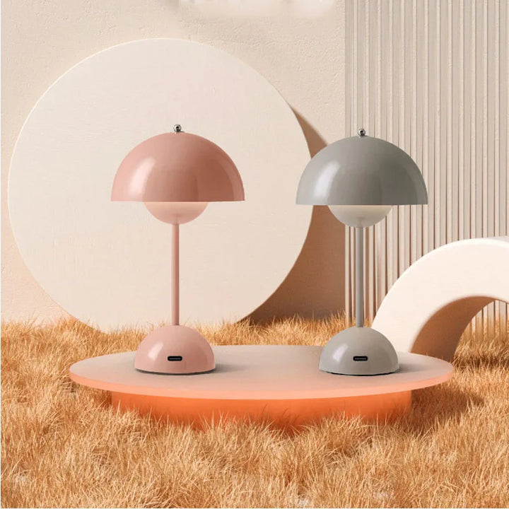 Two table lamps, one pink and one gray, on a round platform with a neutral background.