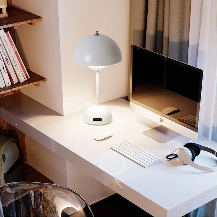 Modern desk setup with computer monitor, keyboard, mouse, and lamp.