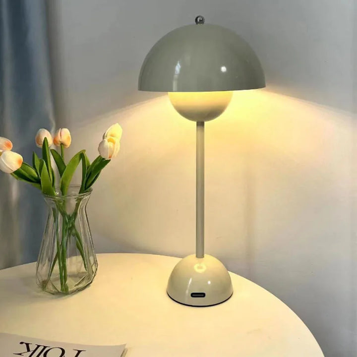 Table lamp with a vase of tulips on a table against a plain background