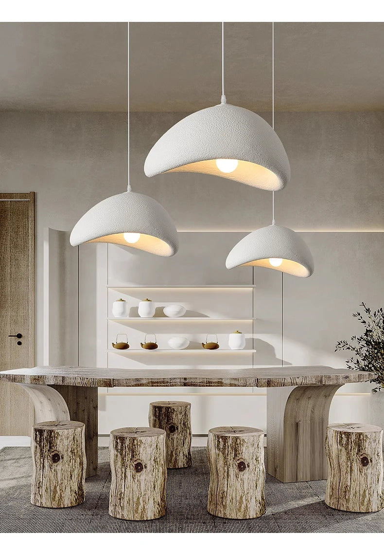 Modern dining area with pendant lights, marble table, and wooden stools.