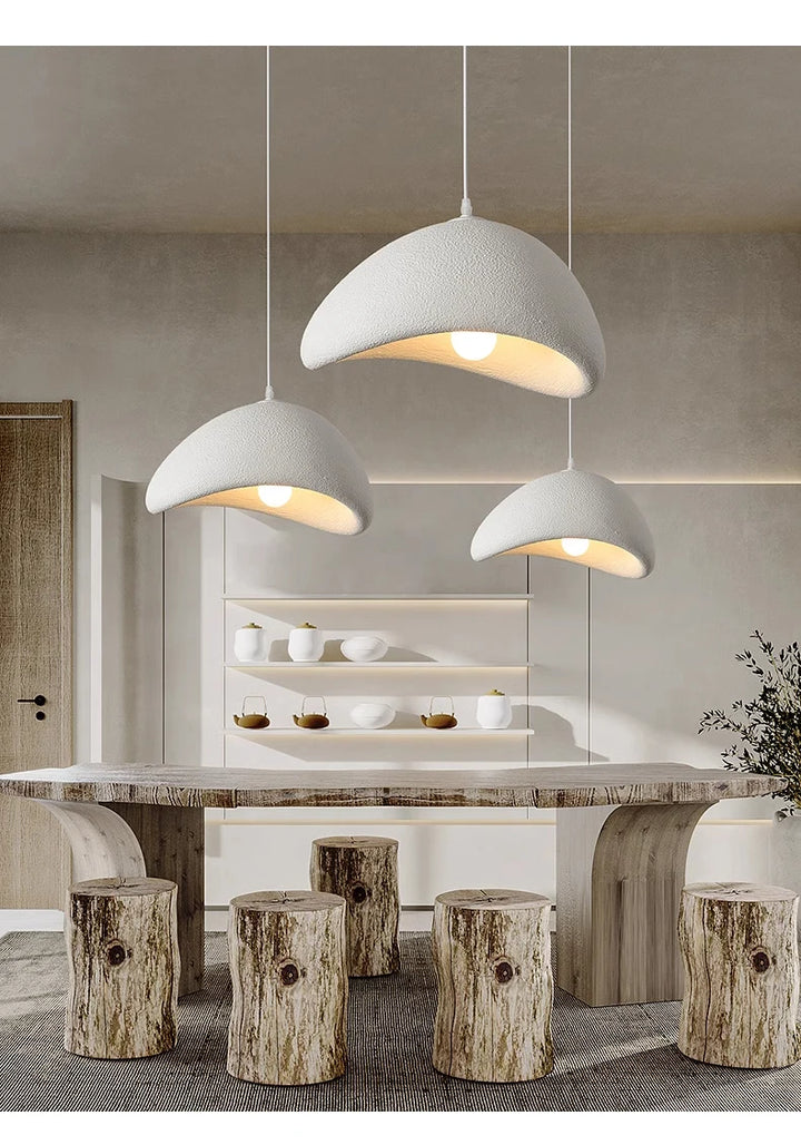 Modern dining area with pendant lights, marble table, and wooden stools.