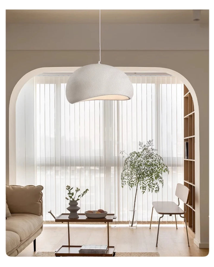 Modern living room with a white pendant light, sofa, coffee table, and decorative plants.