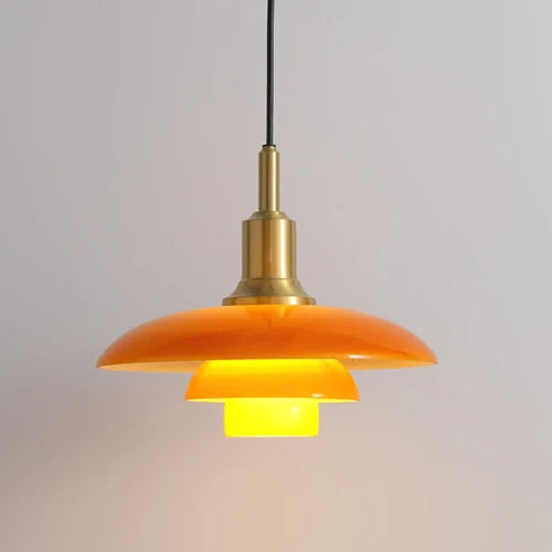 Orange pendant light with brass fixture on a plain background