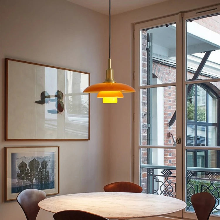 Modern interior with a round table, chairs, framed artwork, and a glass pendant light.