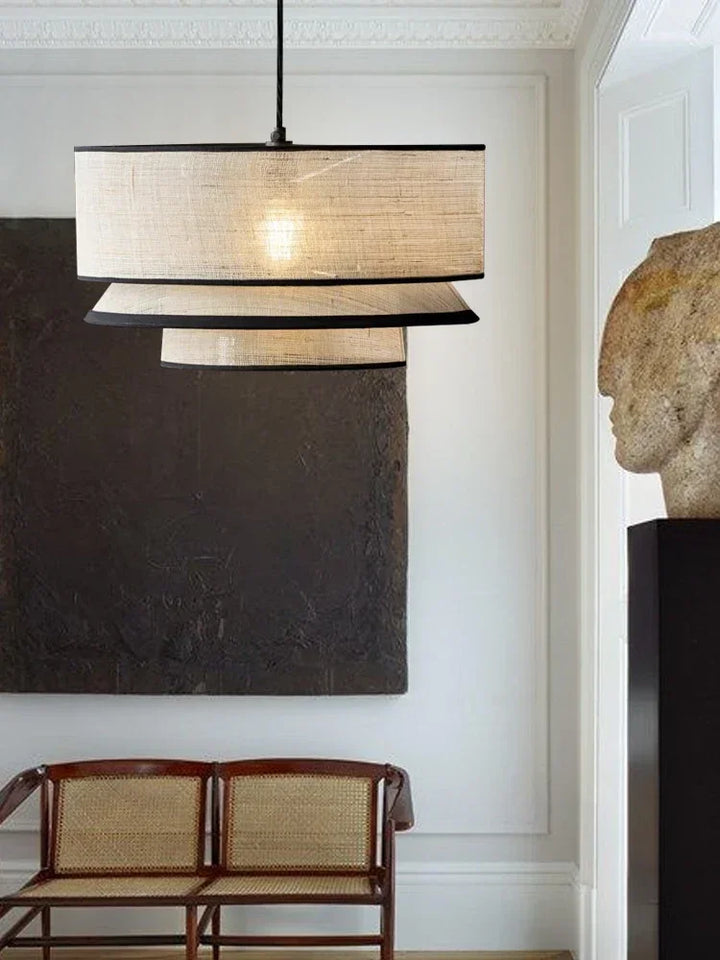 Modern pendant light fixture in a room with a bench and sculpture.