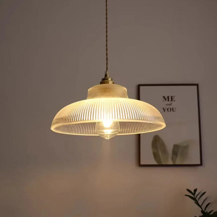 Glass pendant light fixture with a blurred background featuring a framed picture.