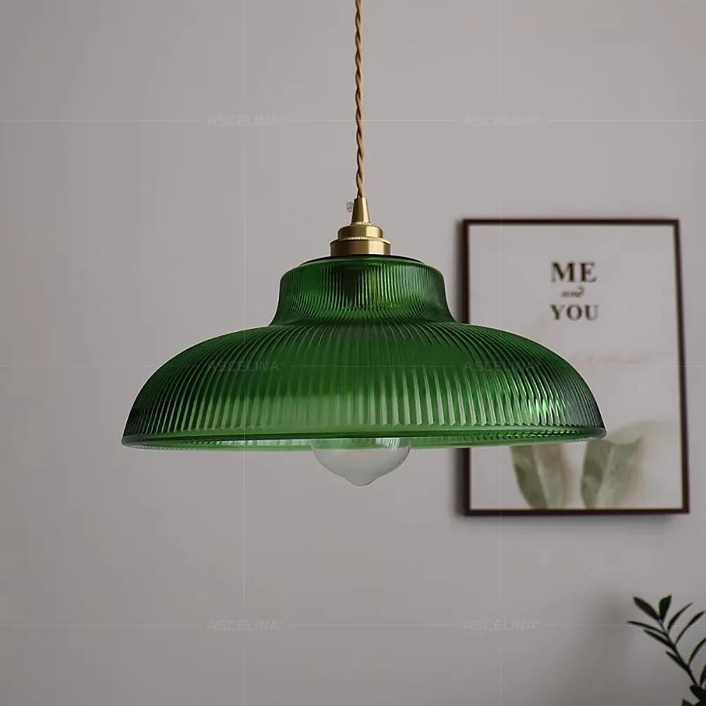 Green pendant lamp hanging against a plain wall with a framed picture.